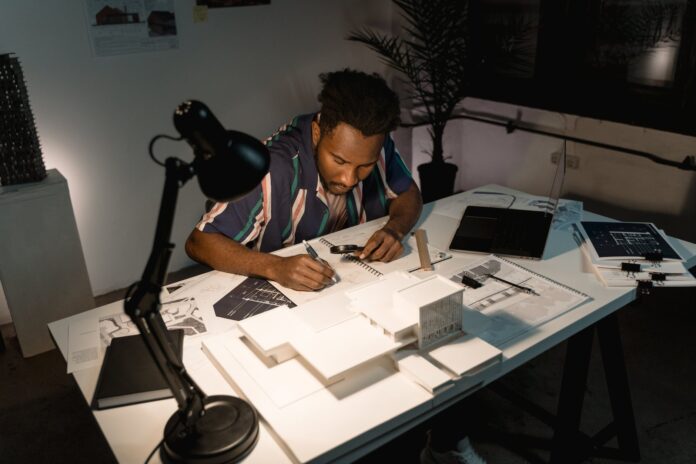 man writing notes on his work table