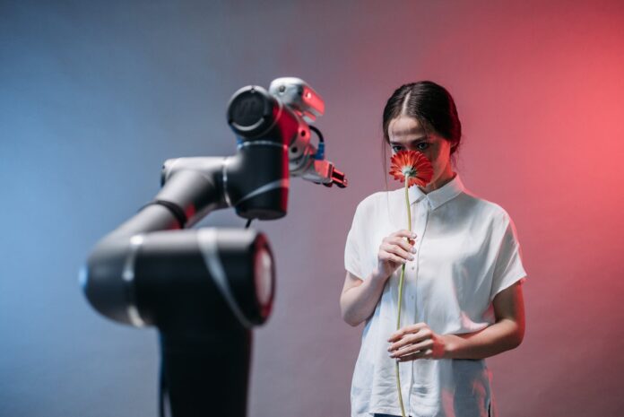 a woman smelling a red flower while staring at a robot