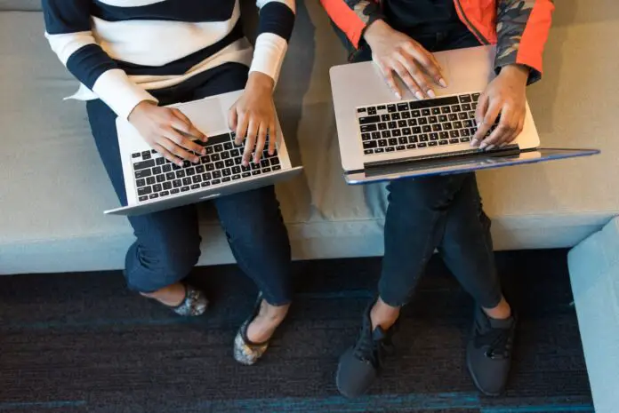 two people holding macbook pro