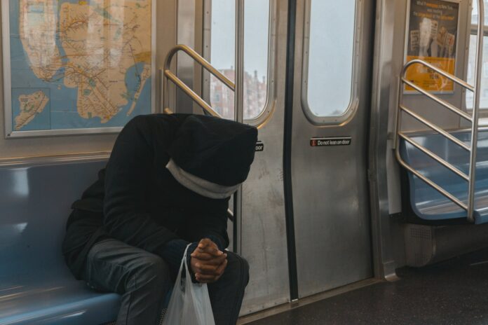 person in black hoodie sitting on train bench