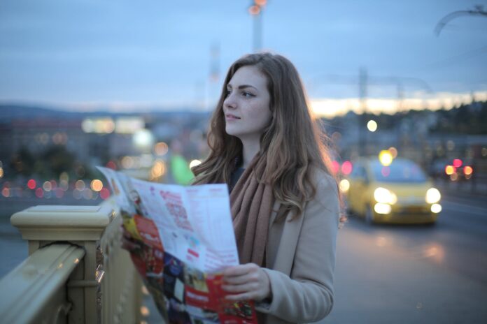 young woman with map looking away on city street