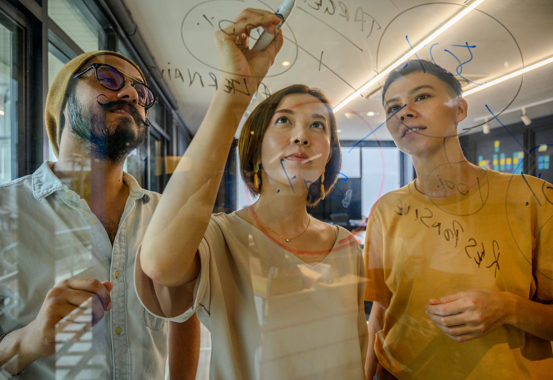 people in an office writing notes on glass window