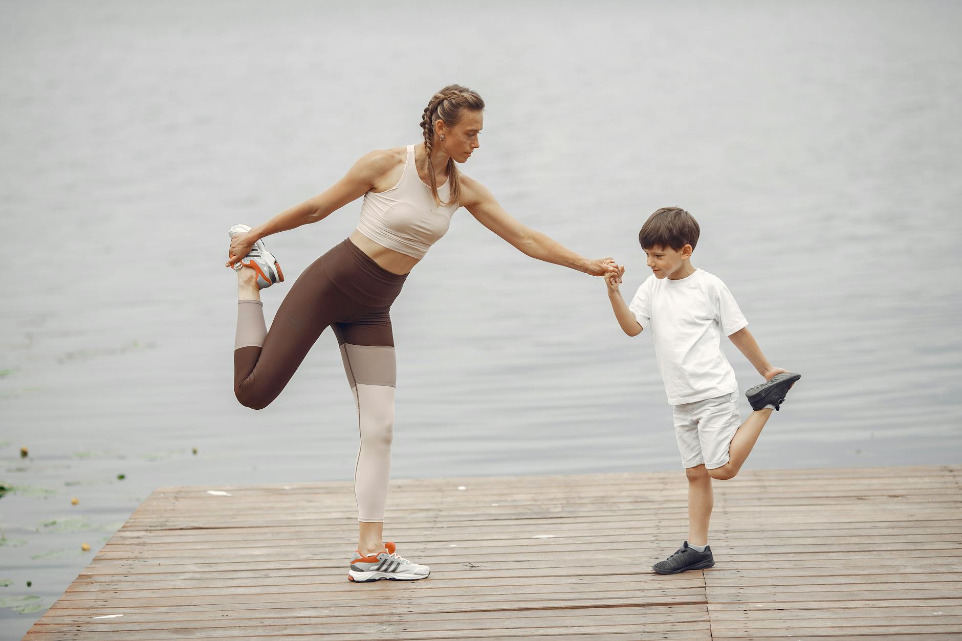 mother and son practising yoga on a pier